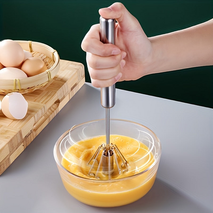 Batidor de cocina manual de acero inoxidable El Rocío batiendo huevos en un bol de cristal sobre una mesa