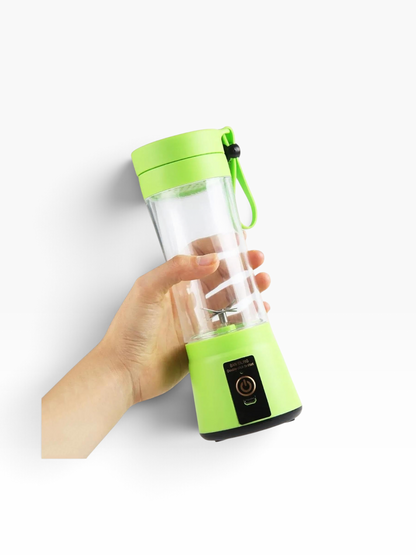 Mano sosteniendo una mini batidora portátil El Rocío de color verde brillante con vaso de 380 ml y carga USB.